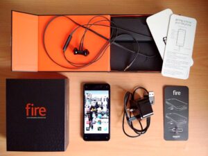 An image of an unboxed Amazon Fire Phone, along with other accessories like a charger and headphones.