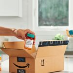 A person grabbing a prescription bottle from an Amazon box