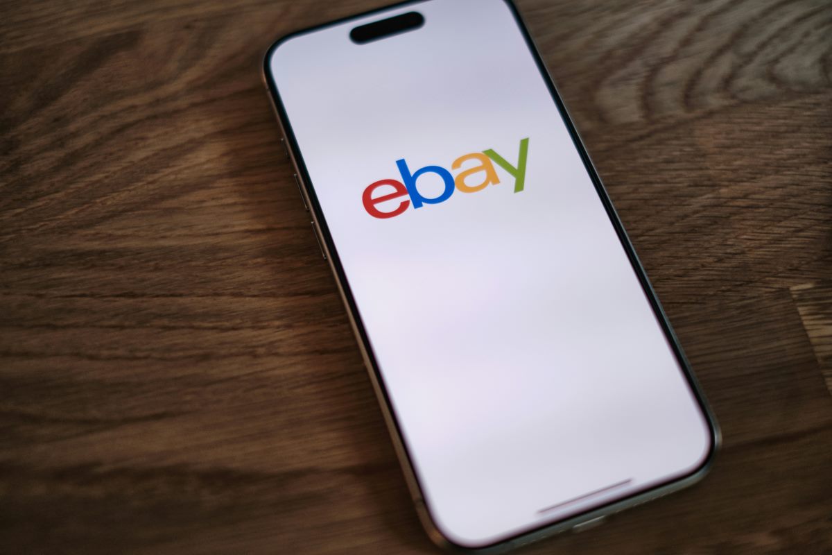A phone on a table with the eBay logo on the screen