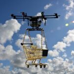 A drone flying through the sky, carrying a shopping cart.
