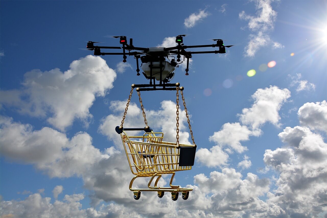 A drone flying through the sky, carrying a shopping cart.