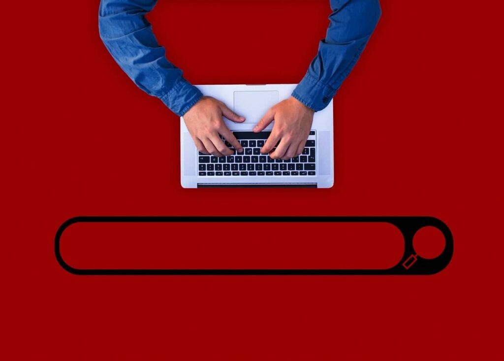 A man performing a search in ecommerce by typing on a computer, right above a search bar.