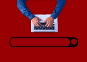 A man performing a search in ecommerce by typing on a computer, right above a search bar.