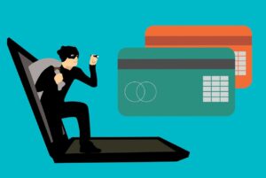 A thief or hacker coming out of a computer to steal credit card information