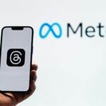 An image of Meta in the background with a person holding a phone