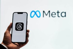 An image of Meta in the background with a person holding a phone