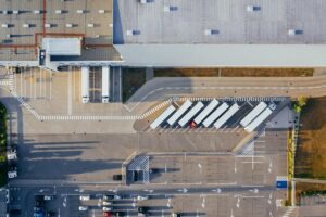 An aerial view of a factory, with several trucks and cars in the parking lot