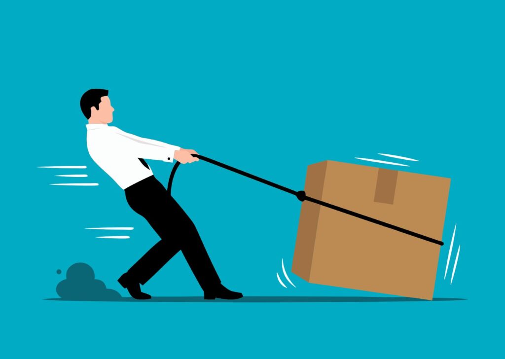 A person struggling to drag a large cardboard box with a rope tied around it