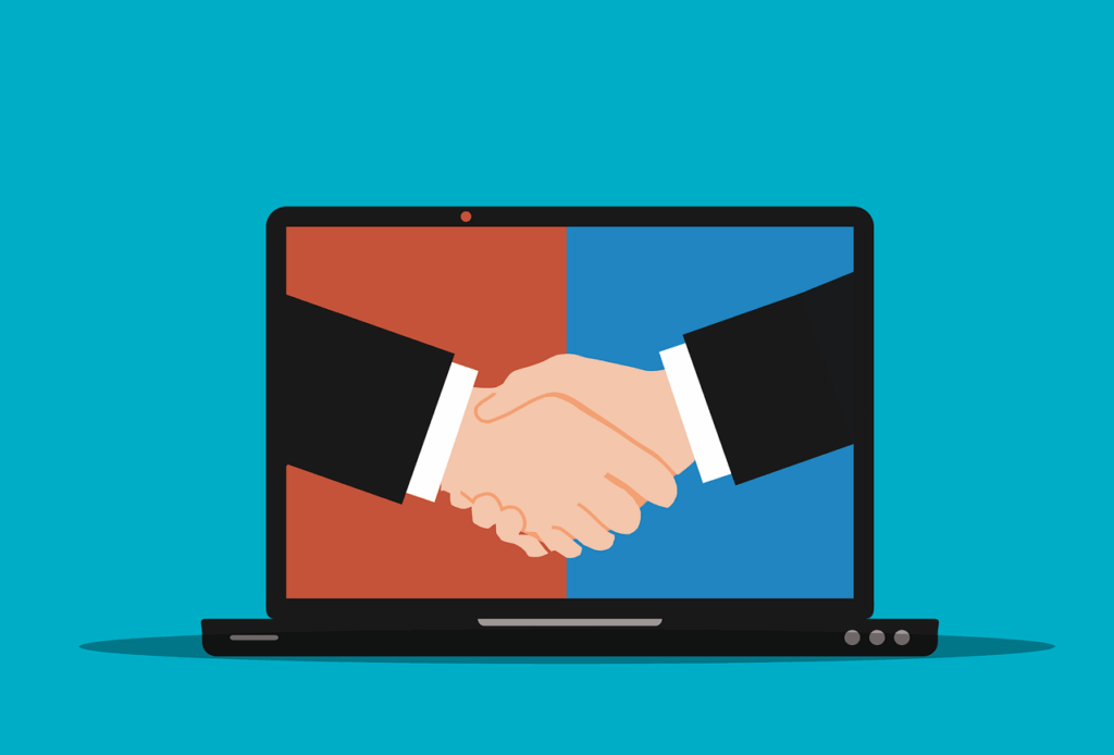 A laptop computer with two arms shaking hands on the screen.