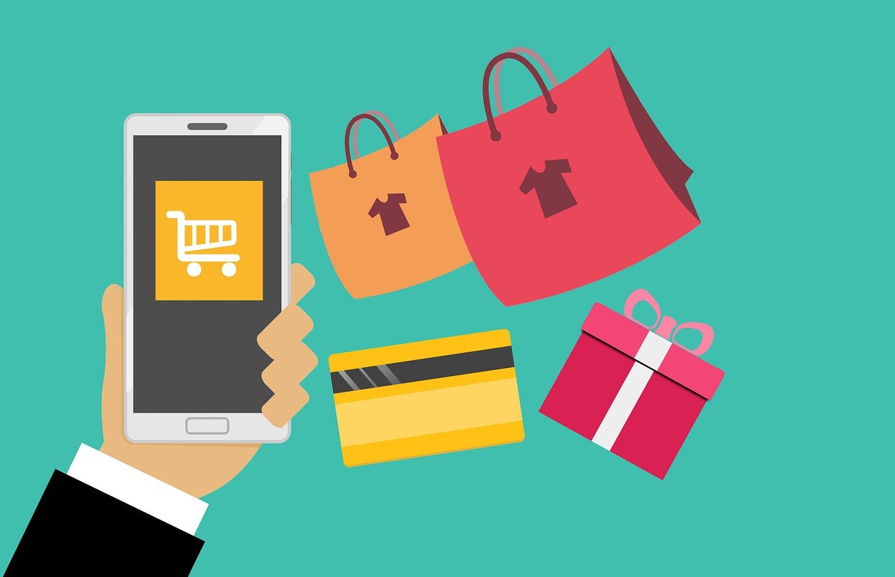 A phone with a shopping cart on it, surrounded by a credit card, gift, and shopping bags.