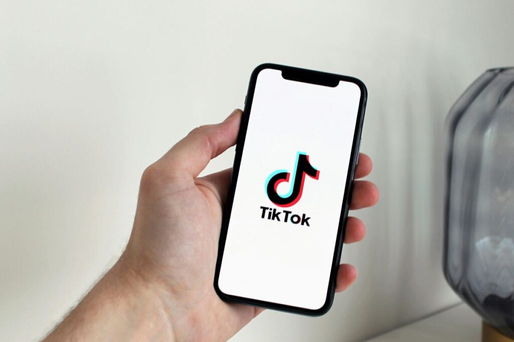 A person holding a cell phone with the TikTok logo on the screen