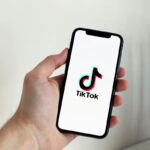 A person holding a cell phone with the TikTok logo on the screen