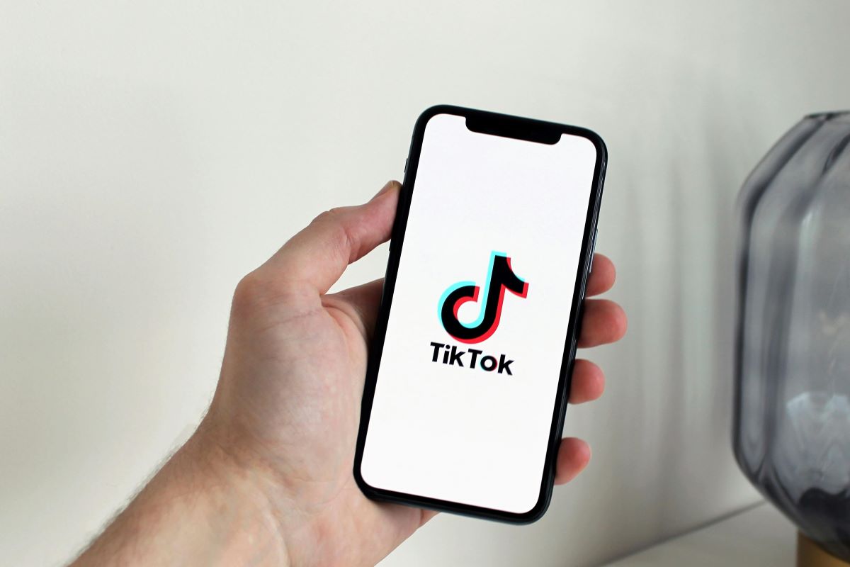 A person holding a cell phone with the TikTok logo on the screen