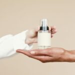 Someone handing a bottle of perfume to another person