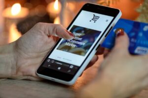 Woman using smartphone for online shopping with credit card in hand.