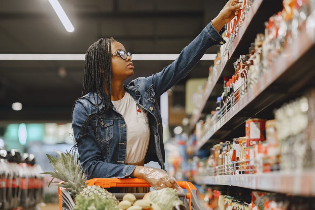 A woman selecting items in a grocery store aisle.