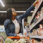 A woman selecting items in a grocery store aisle.