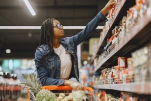 A woman selecting items in a grocery store aisle.
