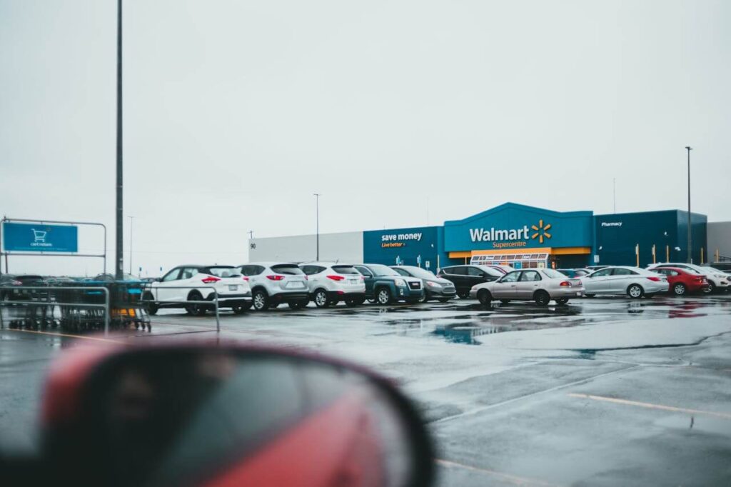A view of a Walmart Supercenter with parked cars and wet pavement.