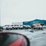 A view of a Walmart Supercenter with parked cars and wet pavement.