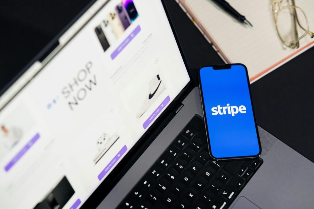 A phone that says Stripe on it, sitting on a laptop with the screen on an online store