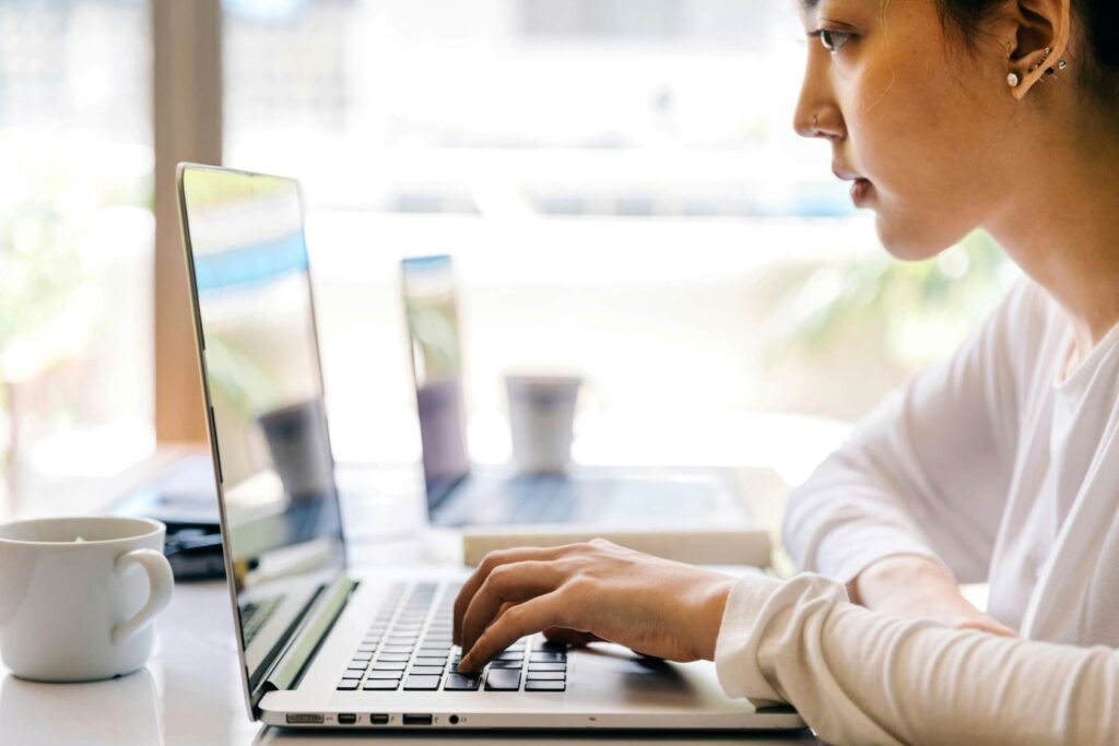 Woman looking at a laptop and typing on the keyboard