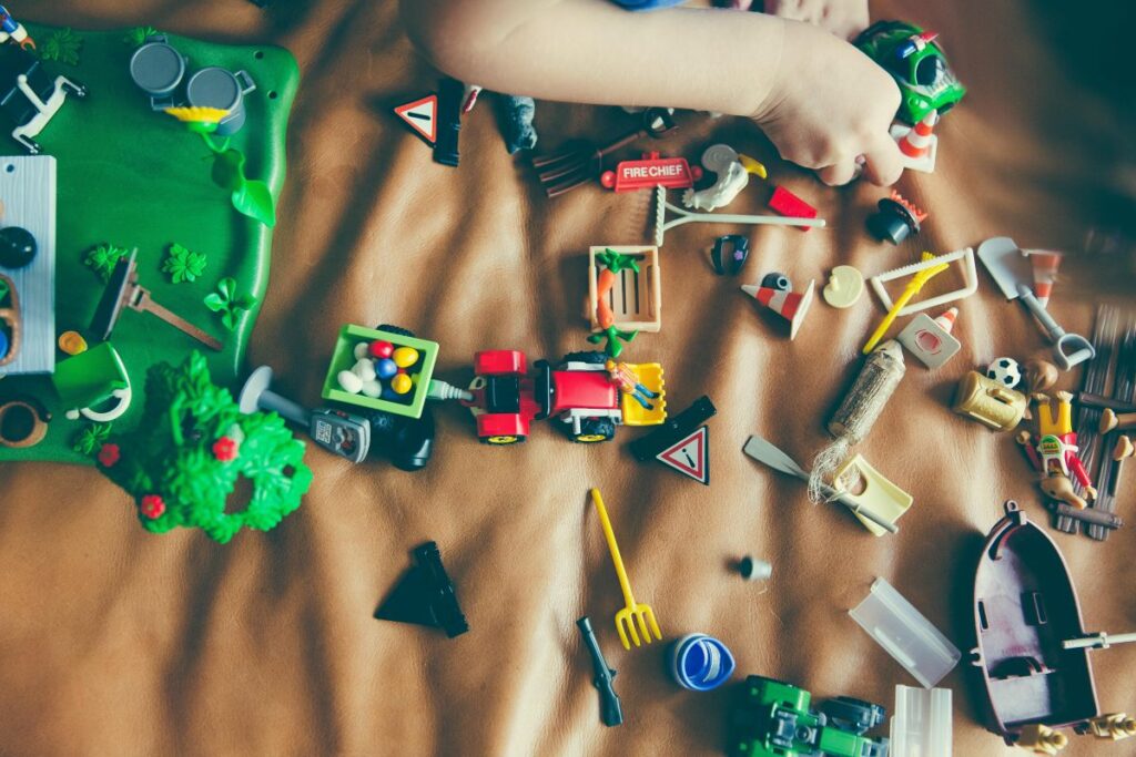 A child’s arm playing with a variety of small toys.