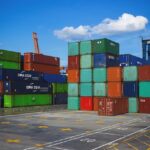 Several large shipping containers stacked on one another, sitting at a port.