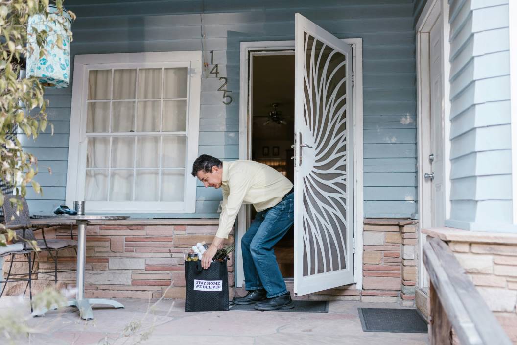 A man picking up a bag of items that was delivered to his door