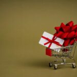 A shopping cart with a credit card wrapped in ribbon and a bow.