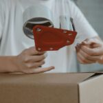 A person getting ready to tape up a cardboard shipping box