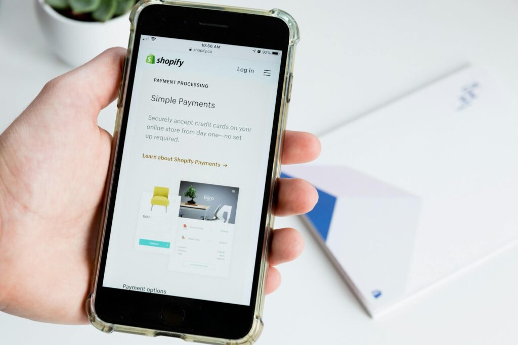 A person holding a phone showing the Shopify Payments platform.