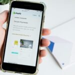 A person holding a phone showing the Shopify Payments platform.