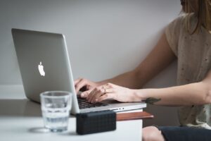 A person sitting at a desk, typing on their laptop computer