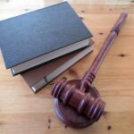 An image of a few books on a table, near a judge’s gavel and sound block.