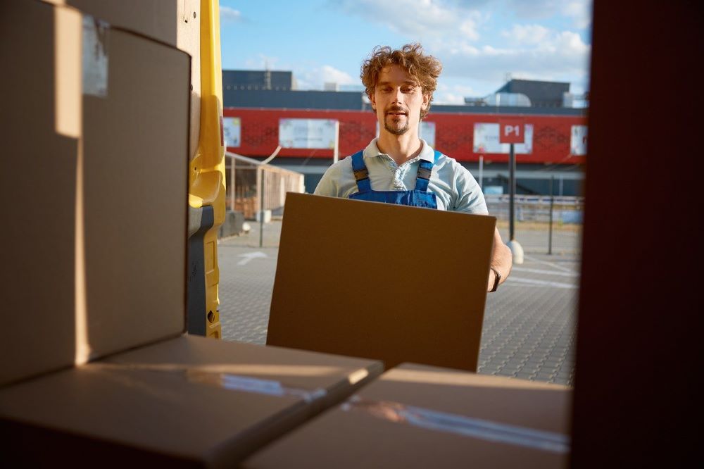 A man loading a shipping box into the back of a vehicle