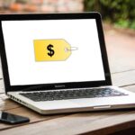 A laptop on a table with a price tag on the screen.