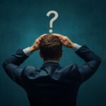 A person with their hands on their head, and a question mark above them